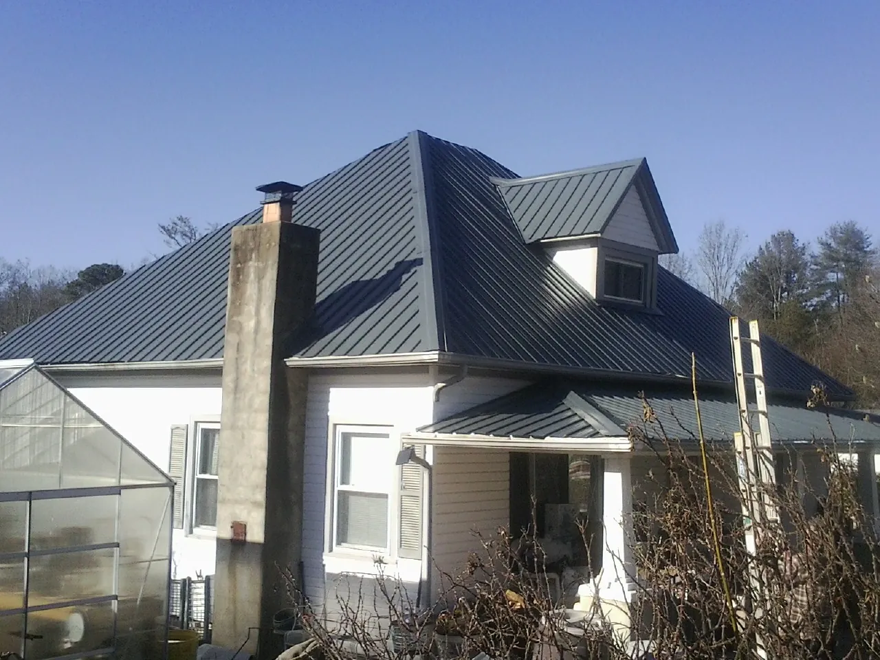 Dark blue standing seam metal roof on a white farmhouse with dormer — Slate & Tile Roof Repair by Roofing Brothers in Collegeville