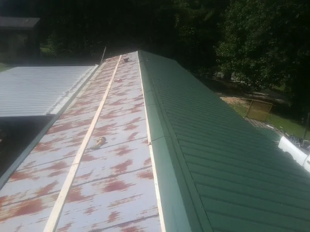 Old rusted panels beside newly installed green metal roofing — Wind Damage Roof Repair by Roofing Brothers in Collegeville