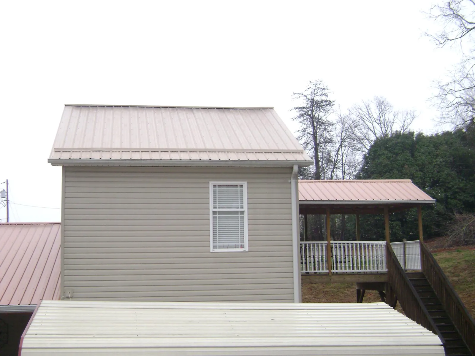 Tan metal roofs on a two story addition and attached porch, from a Roof Replacement job in Collegeville