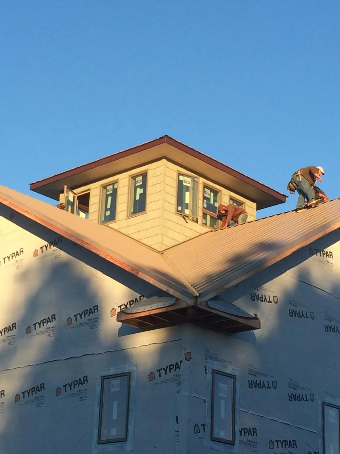 Roofers working around a rooftop cupola on a new metal roof at sunset — Roof Waterproofing in Collegeville by Roofing Brothers